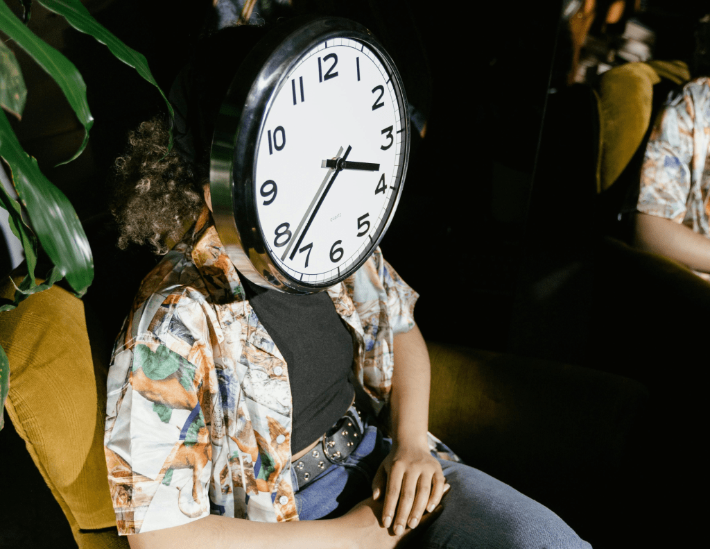 A Silver Round Clock Covering the Person's Face