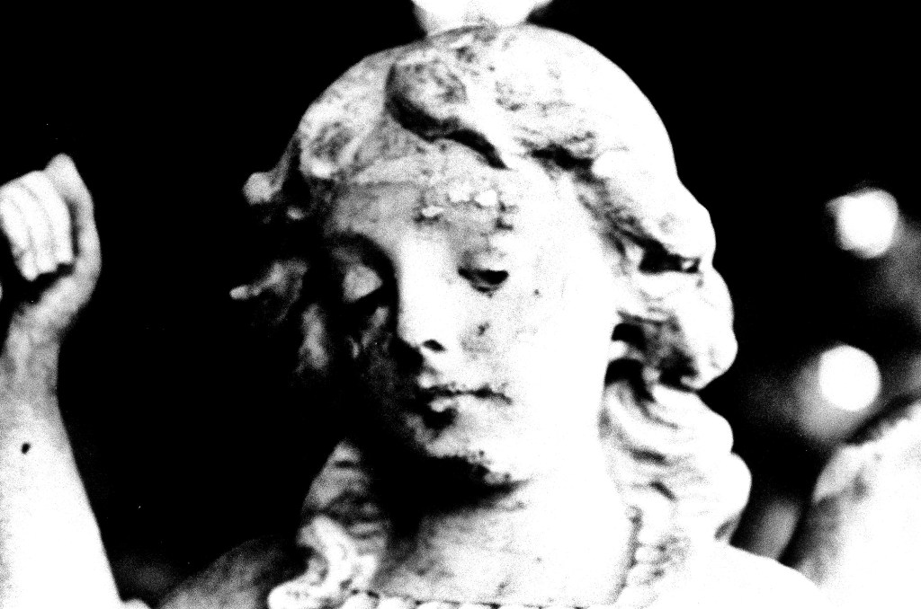 a black-and-white image of an angel statue in a cemetery.